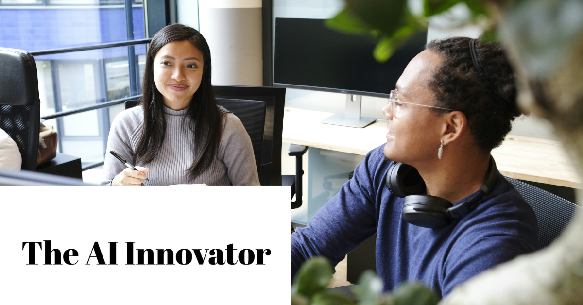 Two people talking in an office setting with a plant in the foreground.
