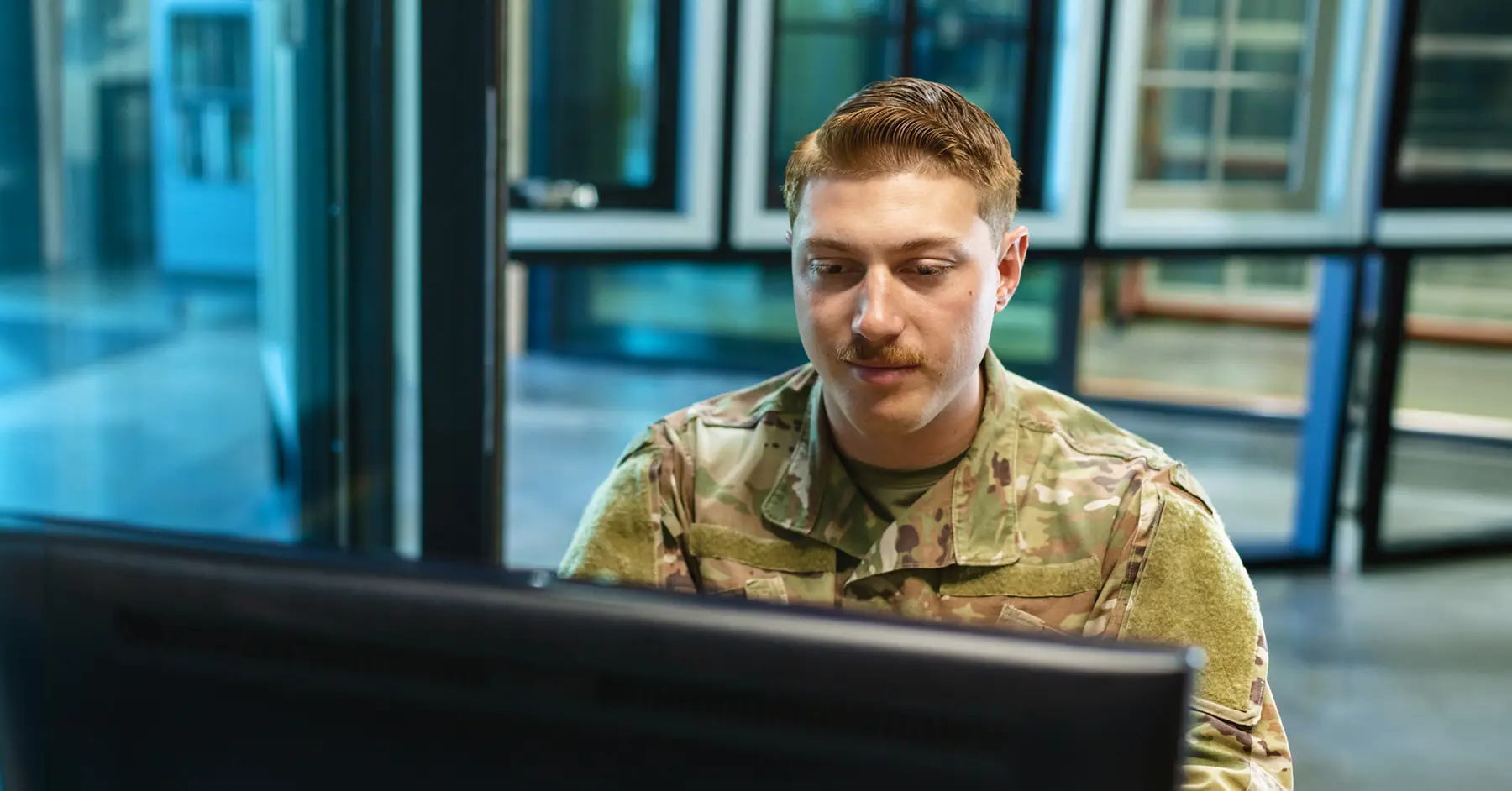 Photo of a soldier at a computer working in Blackboard, an IL4 authorized learning management system