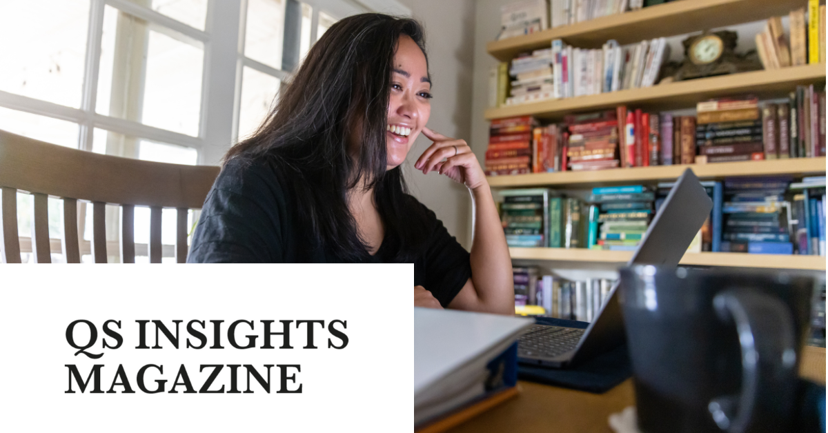 A woman smiling while working on a laptop at a table with a bookshelf filled with books in the background.  Transcribed Text:  QS INSIGHTS MAGAZINE