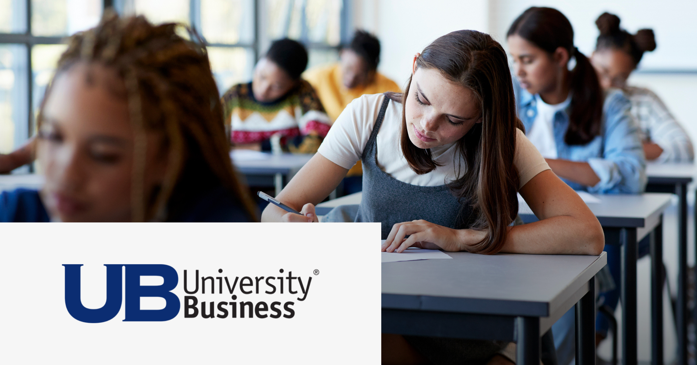 Image of a group of students writing on their notebooks in a classroom. On the lower left corner is placed the University Business logo.