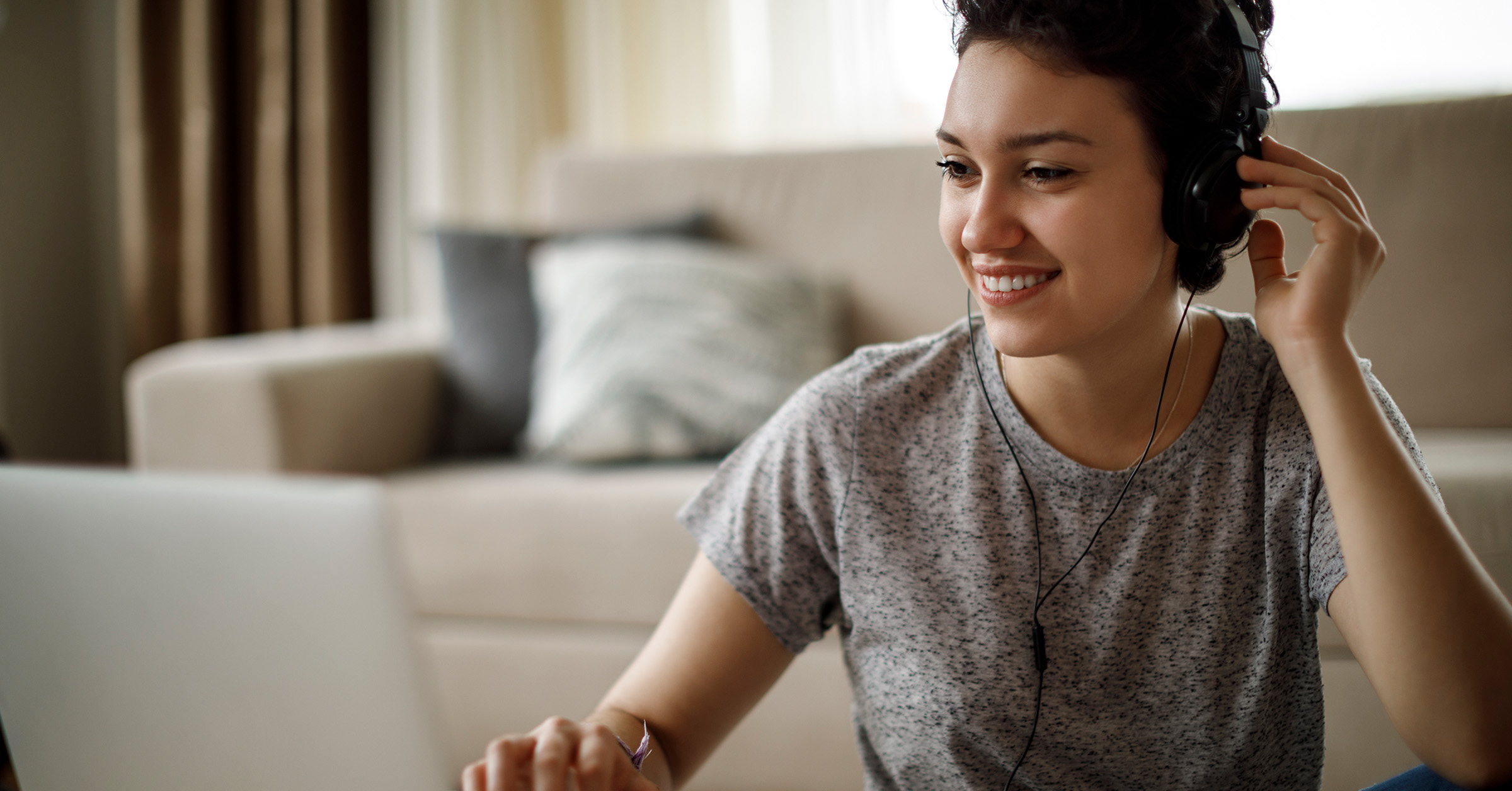 Photo of a woman wearing headphones working at a laptop