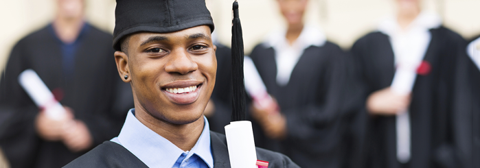 Man wearing cap and gown holding his diploma.